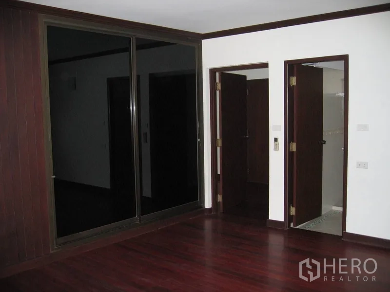 บ้าน ให้เช่าในWatthana, Bangkok - ห้องนอนพื้นไม้สีเข้ม ประตูกระจกบานเลื่อน และทางเข้าห้องน้ำในตัว