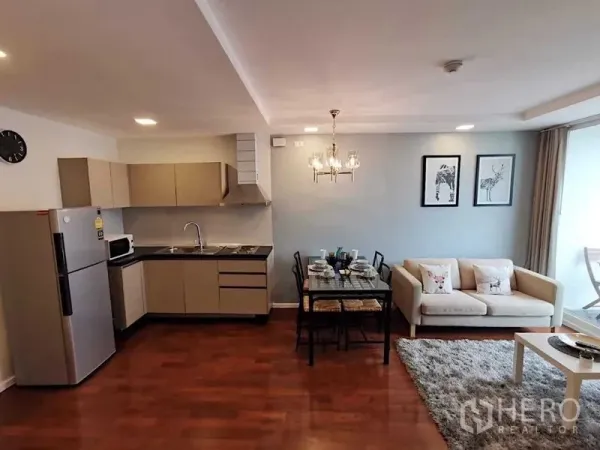 Condominium for sale in Khlong Toei, Bangkok - Open-plan living and dining with fitted kitchen, chandelier, sofa, and balcony doors.
