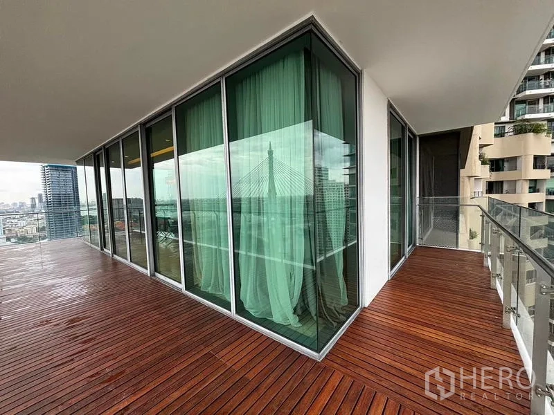 Condominium for rent - Corner wraparound balcony with wooden deck and glass railing.