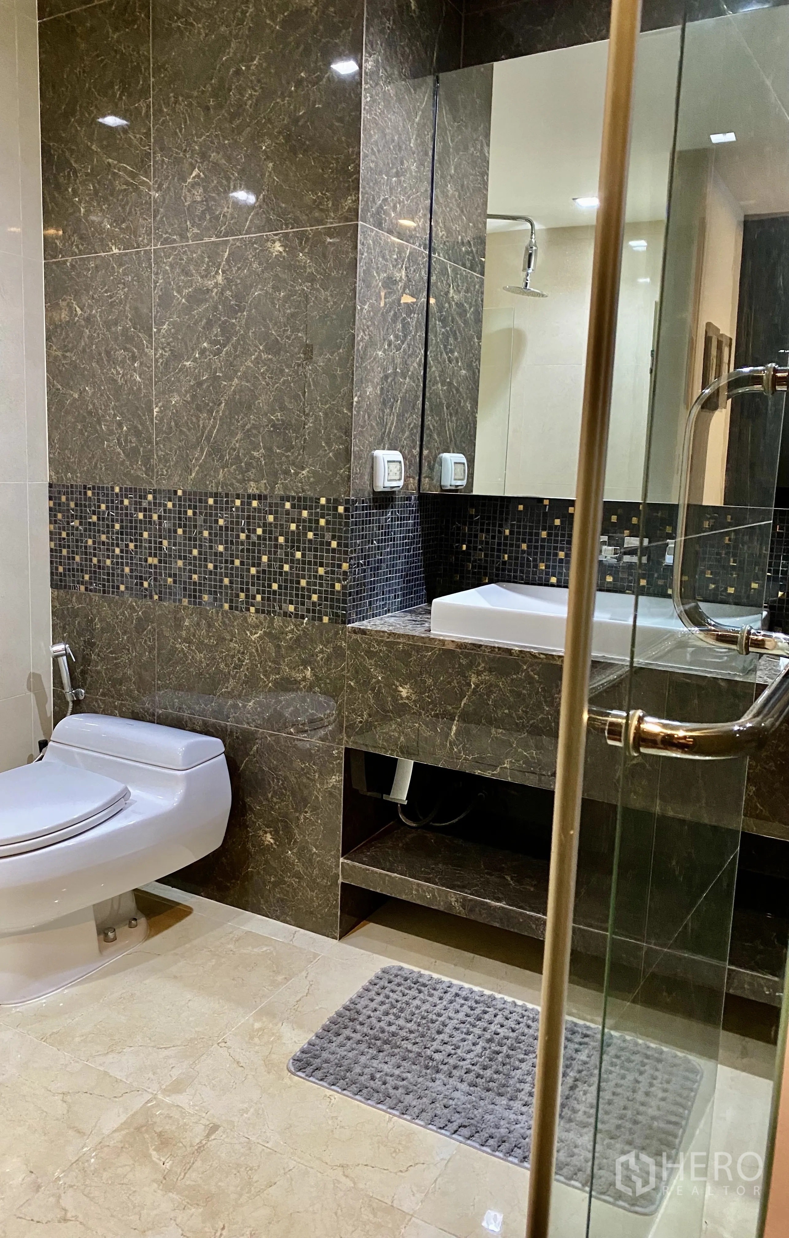 Condominium for rent in Watthana, Bangkok - Modern bathroom with marble tiles, glass shower enclosure, and vanity.