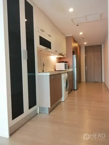 公寓 出租在Watthana, Bangkok - 走廊式厨房，带高柜、水槽、微波炉、冰箱与洗衣机。