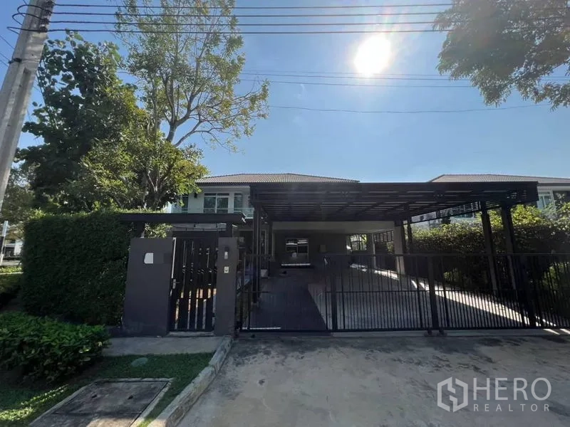 Detached House for rent or sale in Bang Phli, Samut Prakan - Gated detached house exterior with wide covered carport and mature trees.