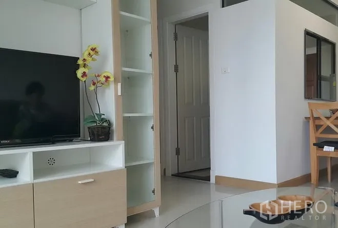 Condominium for rent in Watthana, Bangkok - TV console with open shelving beside the hallway in a clean, minimalist living room.