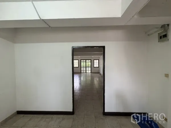 店屋 出租在Phra Khanong, Bangkok - 通过门框望向宽敞明亮的房间，通铺地砖与窗户采光。