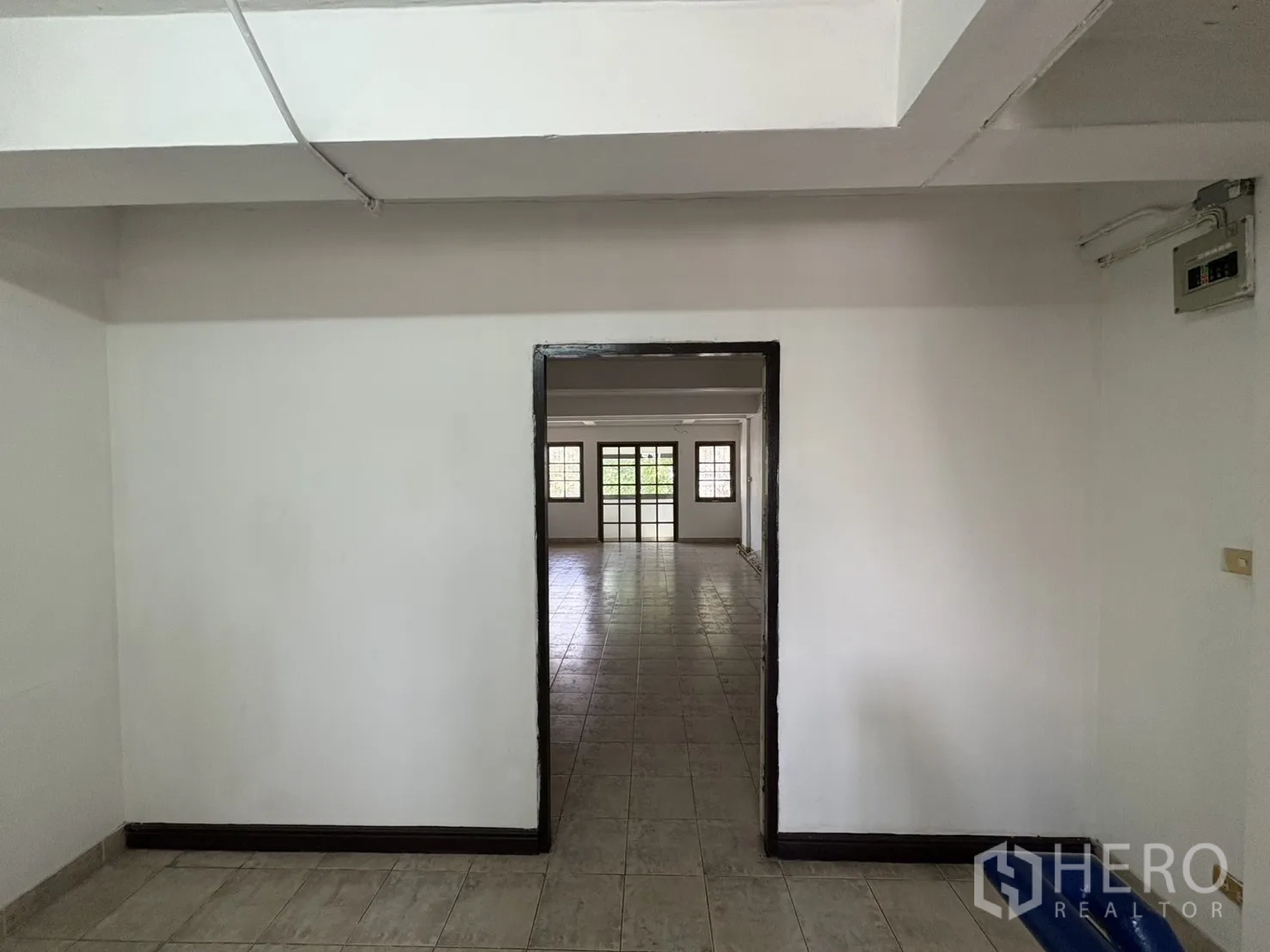 店屋 出租在Phra Khanong, Bangkok - 通过门框望向宽敞明亮的房间，通铺地砖与窗户采光。