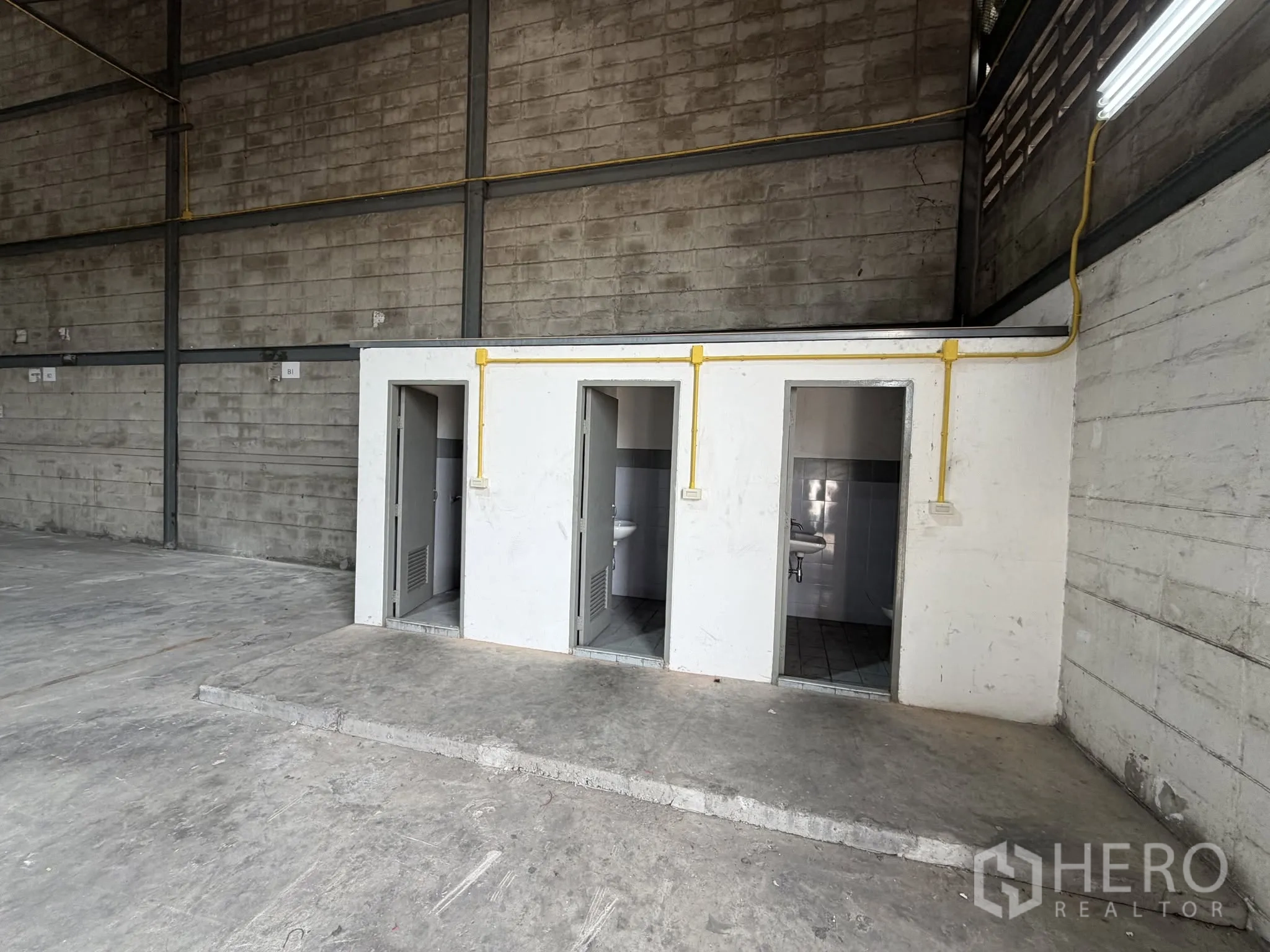 Warehouse for rent in Bang Na, Bangkok - On-site restroom block with multiple stalls and a sink inside the warehouse.