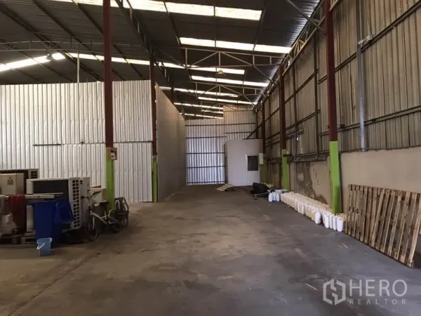 คลังสินค้า ให้เช่าในBang Na, Bangkok - ทางเดินยาวในโกดัง มีผนังกั้นเมทัลชีท ห้องใช้งานขนาดเล็ก และโครงหลังคาเปิดโล่งเหนือพื้นคอนกรีต