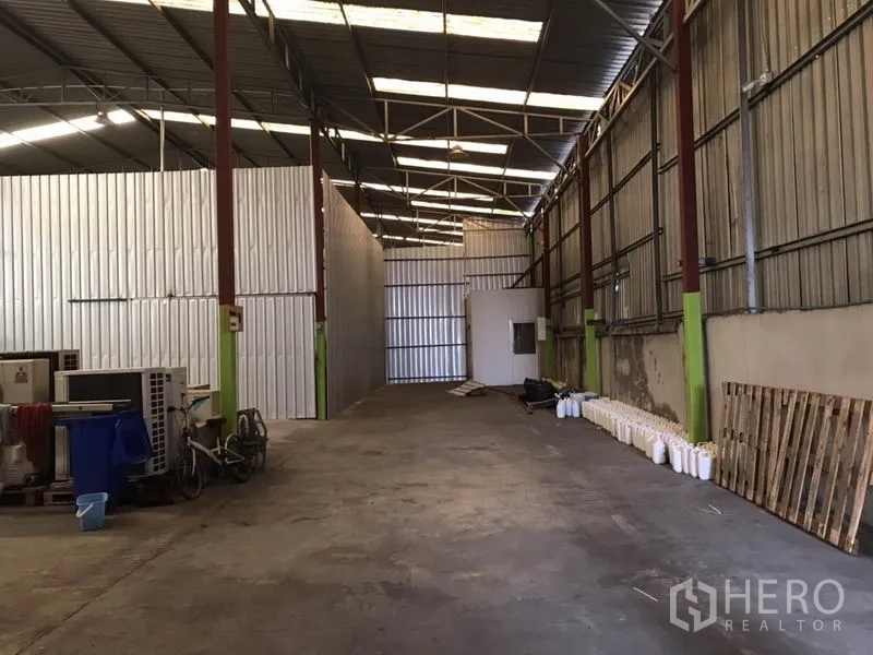 คลังสินค้า ให้เช่าในBang Na, Bangkok - ทางเดินยาวในโกดัง มีผนังกั้นเมทัลชีท ห้องใช้งานขนาดเล็ก และโครงหลังคาเปิดโล่งเหนือพื้นคอนกรีต