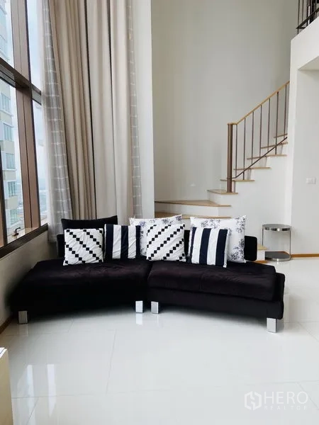 คอนโด ให้เช่าในKhlong Toei, Bangkok - มุมนั่งเล่นพร้อมโซฟา ผ้าม่านสูง และบันไดขึ้นชั้นลอย