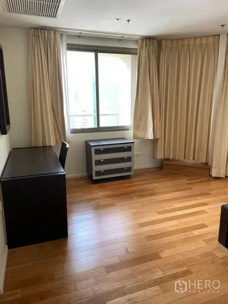 公寓 出租在Khlong Toei, Bangkok - 采光充足的房间，设书桌、抽屉柜与浅色窗帘，木地板。