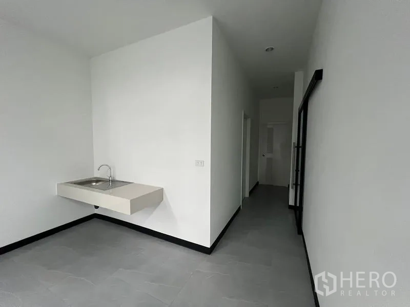 Warehouse for rent in Chon Buri - Clean pantry area with wall-mounted sink and corridor leading to restrooms.