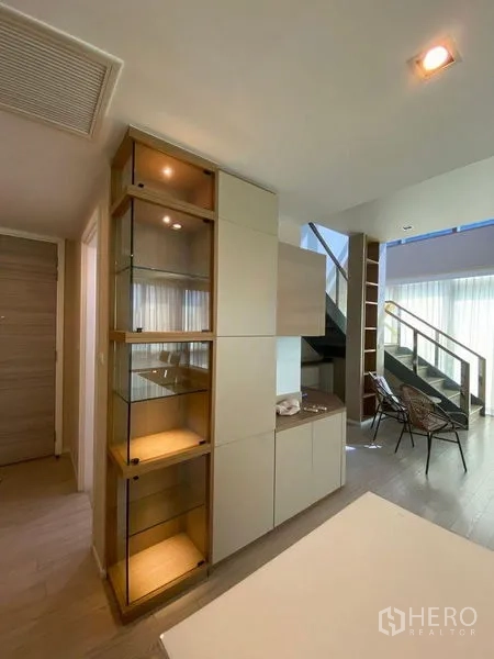 คอนโด ขายในWatthana, Bangkok - พื้นที่อยู่อาศัยแบบโอเพนแพลน มีตู้โชว์กระจก บันได และหน้าต่างเต็มผนัง
