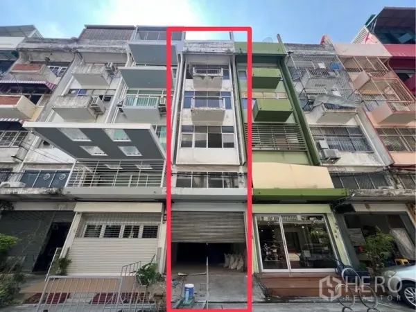 Shophouse for rent in Bangkok - Four-storey shophouse exterior with roller shutter and balconies highlighted in red, set among adjoining townhouses.