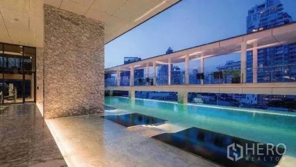 คอนโด ให้เช่าหรือขายในKhlong Toei, Bangkok - สระว่ายน้ำลอยฟ้าของคอนโดพร้อมทางเดินหินอ่อนและวิวเมืองยามค่ำ