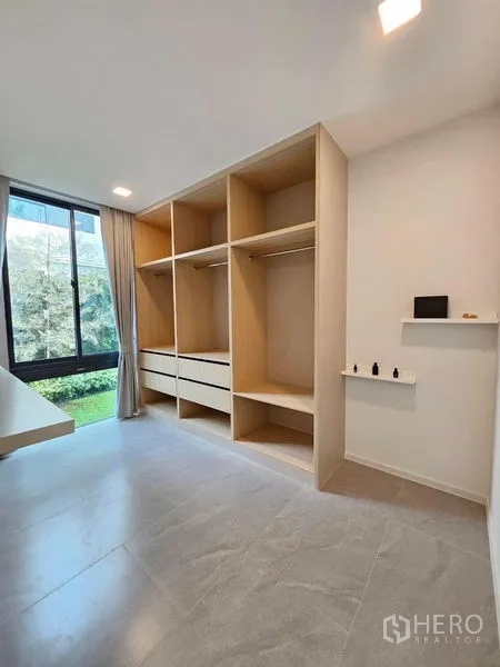 Detached House for rent - Walk‑in dressing room with built‑in open wardrobes and a garden‑view window.
