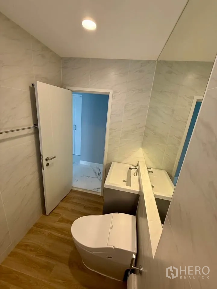 Detached House for rent in Don Mueang, Bangkok - Compact bathroom with wood-look flooring, wall mirror, and toilet.