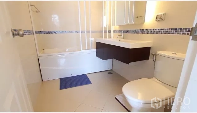 Condominium for rent in Watthana, Bangkok - Second bathroom featuring a bathtub, white vanity and toilet with blue mosaic trim.