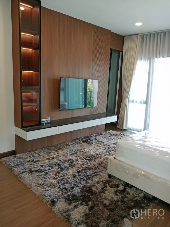 Detached House for rent in Bang Phli, Samut Prakan - Bedroom TV wall with built-in cabinet, display shelves and mounted screen.