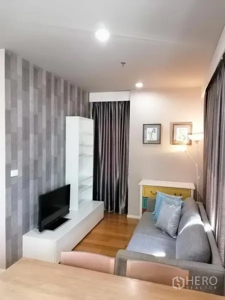 คอนโด ให้เช่าในWatthana, Bangkok - ห้องนั่งเล่นอบอุ่น ชั้นวางทีวี ผนังตกแต่ง และโซฟาข้างผ้าม่านทึบ