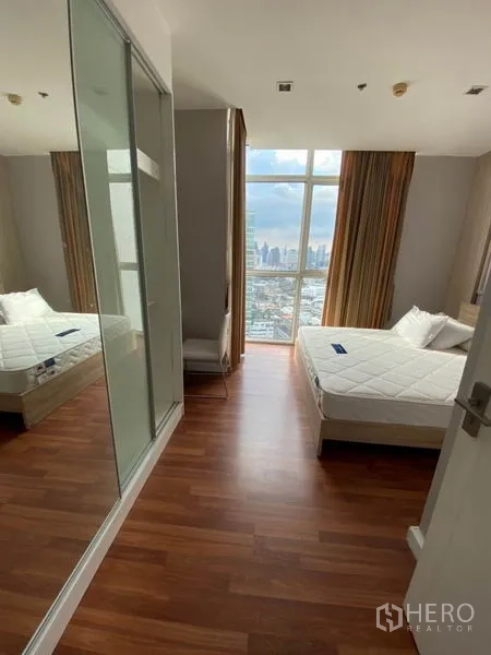 Condominium for rent in Watthana, Bangkok - Hallway to bedroom featuring mirrored sliding wardrobe and full-height window with skyline outlook