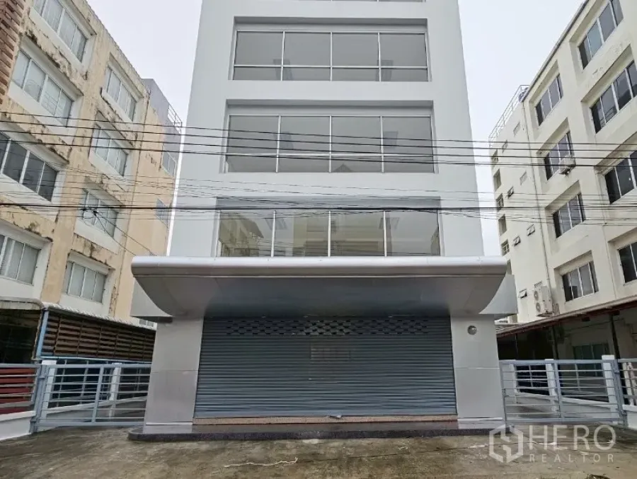 办公空间 出租在Bueng Kum, Bangkok - 五层办公楼立面，大片玻璃窗与卷帘门。