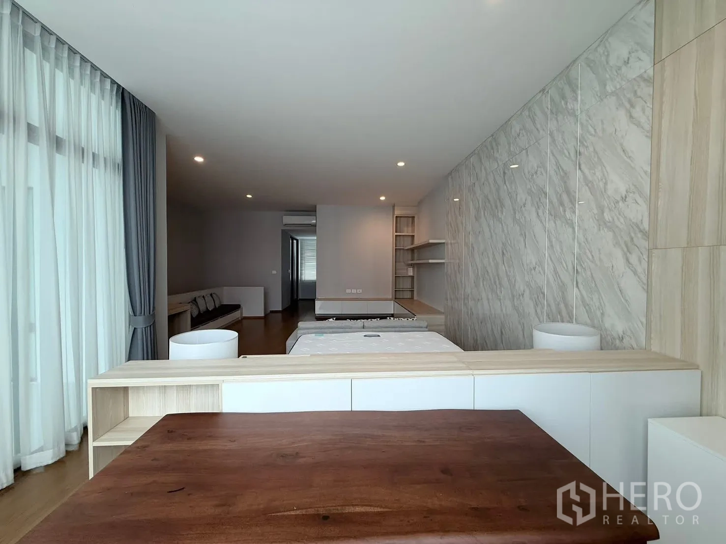 Townhouse for rent in Saphan Sung, Bangkok - Bright suite with bed, sofa, wood floors and a marble accent wall.