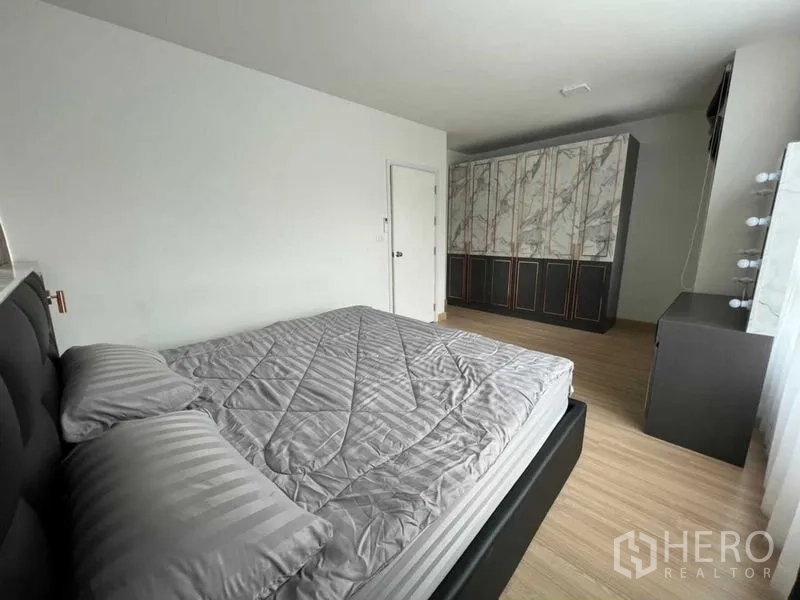 联排别墅 出租在Wang Thonglang, Bangkok - 宽敞卧室，双人床、仿大理石衣柜、梳妆台与木地板。