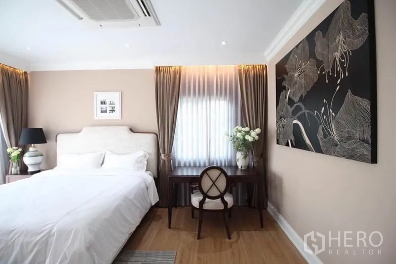 独立式住宅 出租或出售在Lat Phrao, Bangkok - 卧室角落，带写字桌与大型花卉挂画。