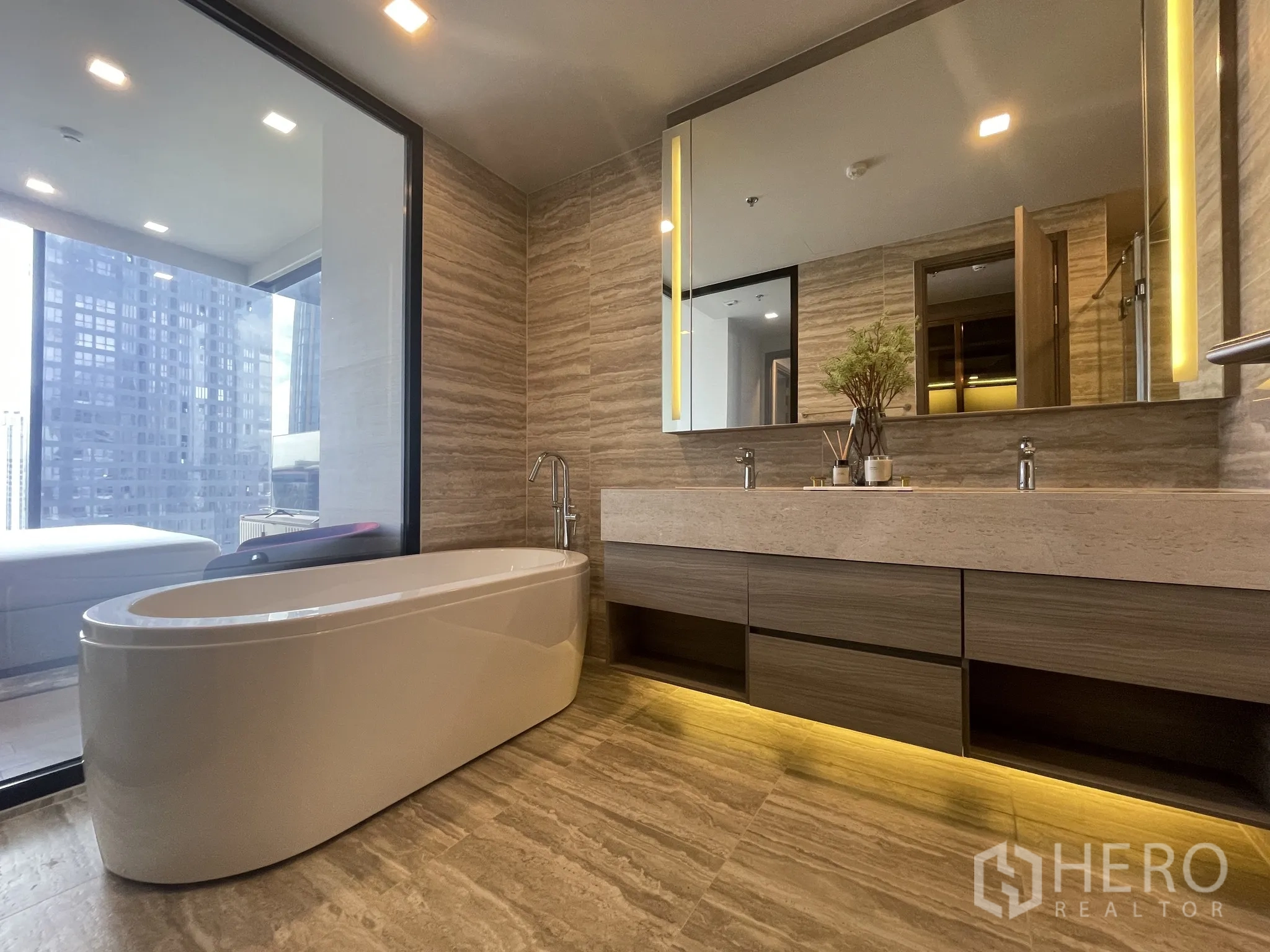 Condominium for rent in Watthana, Bangkok - Luxury bathroom with freestanding bathtub and double-sink vanity facing a window.
