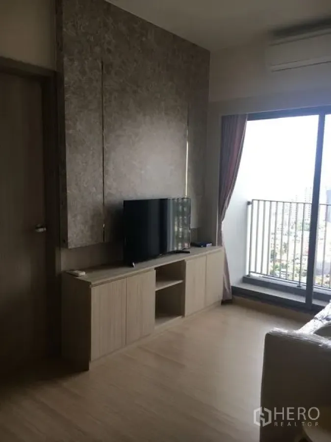 Condominium for sale - Living room with TV cabinet and sliding glass door opening to a balcony with city view.