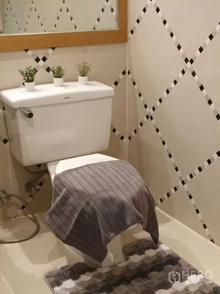 คอนโด ให้เช่าในKhlong Toei, Bangkok - ห้องน้ำกรุกระเบื้องลายตารางขาวดำ โถสุขภัณฑ์ใต้มีกระจกกรอบไม้และกระถางต้นไม้เล็ก