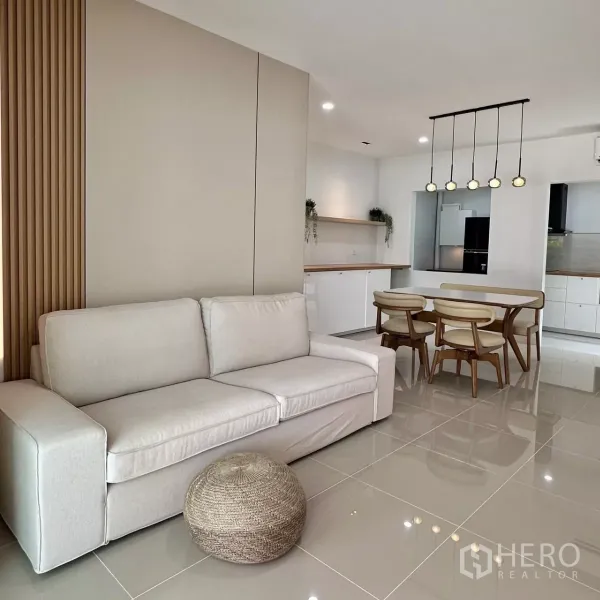 Townhouse for rent in Bang Phli, Samut Prakan - Open-plan lounge with beige sofa next to a dining set and feature wall.