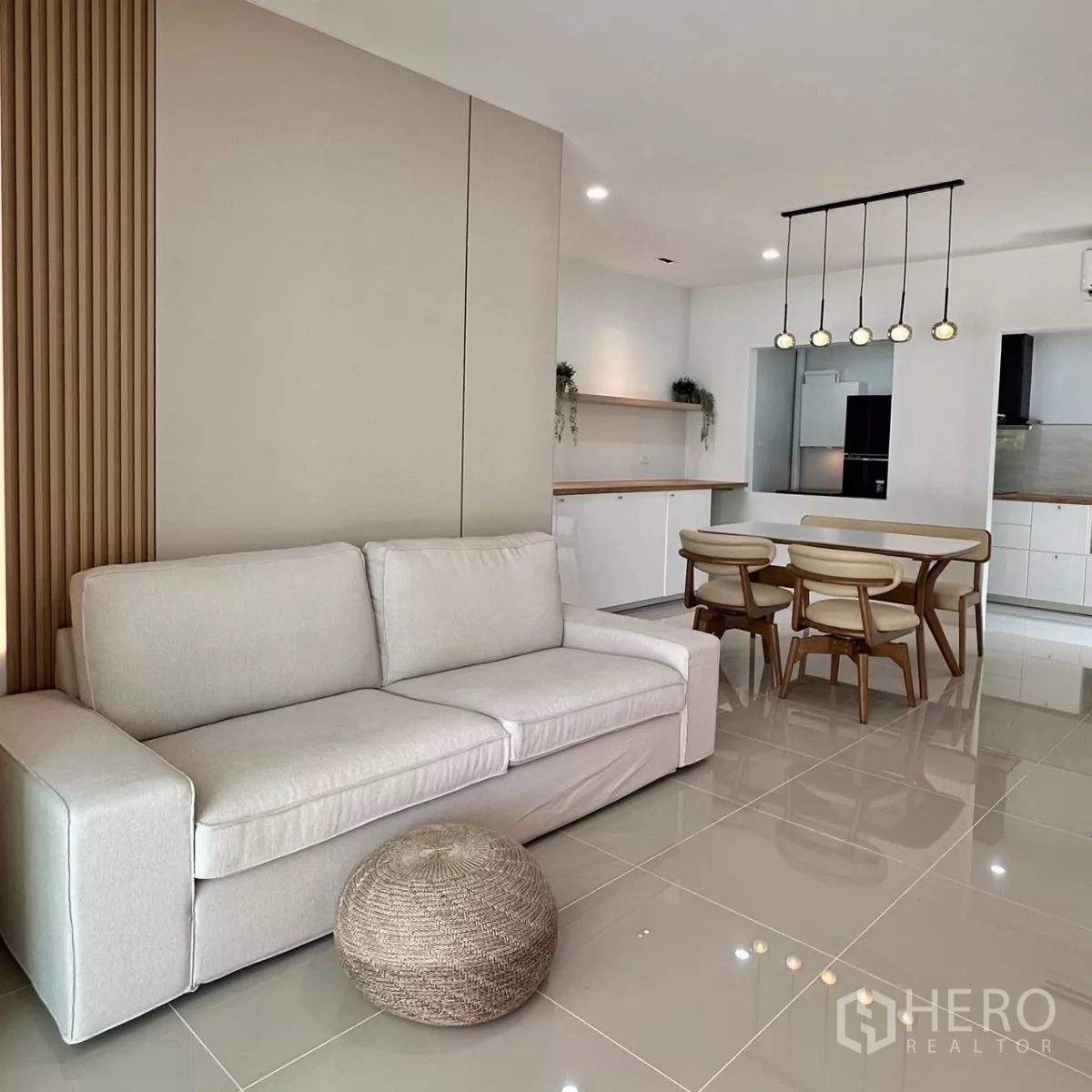 Townhouse for rent in Bang Phli, Samut Prakan - Open-plan lounge with beige sofa next to a dining set and feature wall.