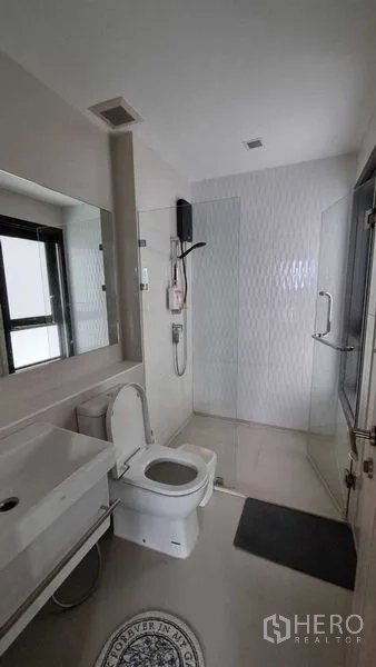 Condominium for sale in Pathum Wan, Bangkok - Modern bathroom with glass shower enclosure, vanity and window