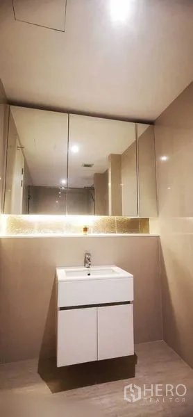 Condominium for rent in Watthana, Bangkok - Modern bathroom with glossy tiles, wide mirrored cabinets and a white vanity.
