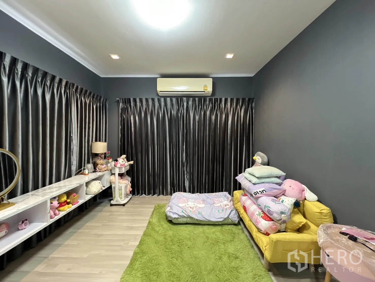 บ้าน ให้เช่าหรือขายในLat Krabang, Bangkok - ห้องนอนใหญ่ ผนังเข้ม โซฟาสีเหลือง และพรมสีเขียว