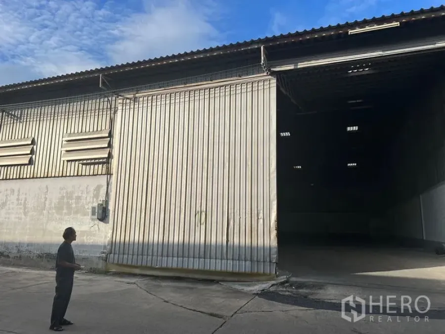 Warehouse for rent in Samut Prakan - Exterior of the warehouse with a large 6×6 m sliding metal door and concrete loading area.