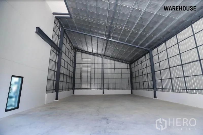 Warehouse for rent in Wang Thonglang, Bangkok - High-ceiling steel-frame warehouse bay with concrete floor and metal cladding.