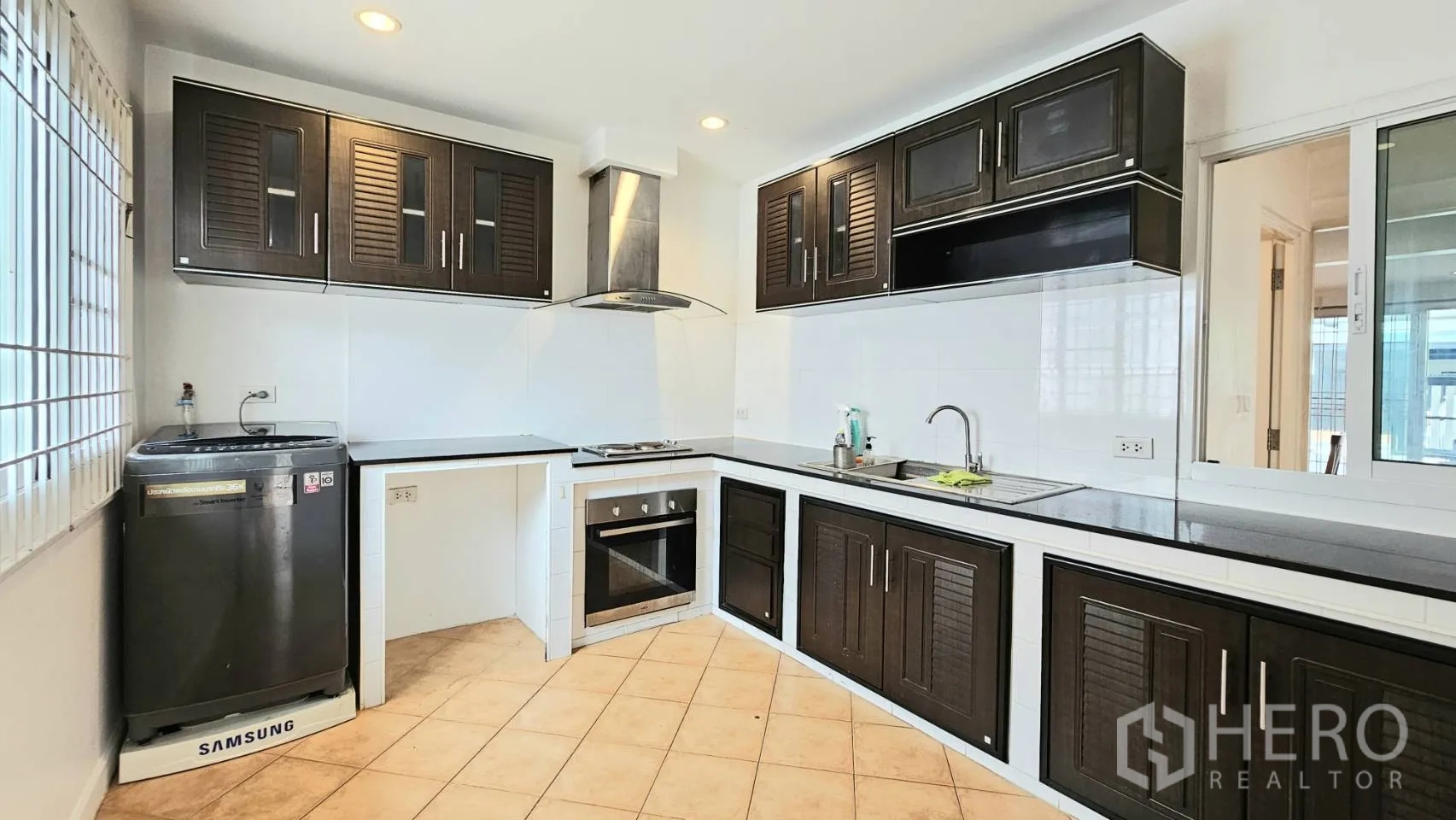 Detached House for rent in Saphan Sung, Bangkok - Wide L-shaped kitchen with dark cabinets, double sink, and ample counter space.