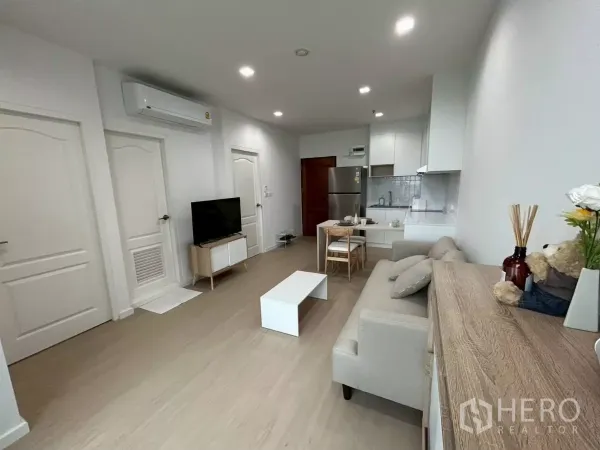 公寓 出租在Bang Rak, Bangkok - 采光充足的开放式客厅，配沙发、电视、餐桌与白色厨房，翻新公寓。