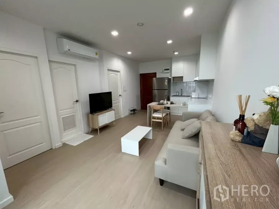 公寓 出租在Bang Rak, Bangkok - 采光充足的开放式客厅，配沙发、电视、餐桌与白色厨房，翻新公寓。