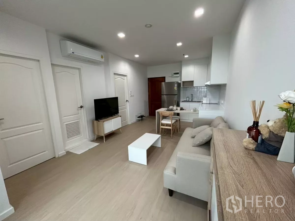 公寓 出租在Bang Rak, Bangkok - 采光充足的开放式客厅，配沙发、电视、餐桌与白色厨房，翻新公寓。