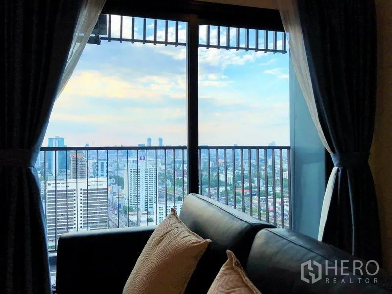 คอนโด ขายในSuan Luang, Bangkok - วิวเมืองจากระเบียง เห็นราวกันตก กรอบด้วยผ้าม่านและโซฟา