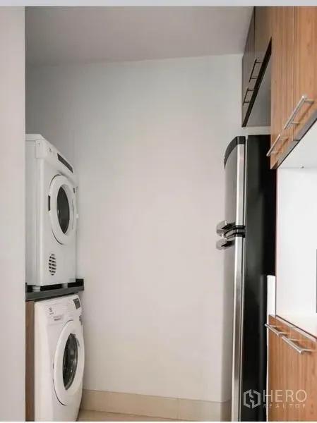 公寓 出租在Sathon, Bangkok - 洗衣角落，叠放式洗衣机与烘干机，旁有高身冰箱。