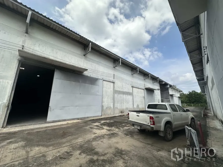 คลังสินค้า ให้เช่าในPhra Nakhon Si Ayutthaya - อาคารโกดังเรียงยาว ประตูเปิดและรถกระบะจอดด้านหน้า