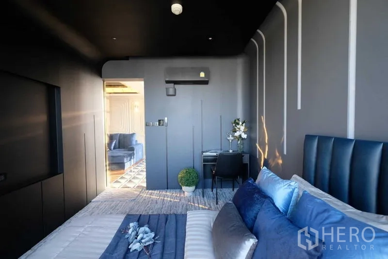 คอนโด ขาย - ห้องนอนมองออกสู่พื้นที่นั่งเล่น มีมุมทำงานและพรมฟู