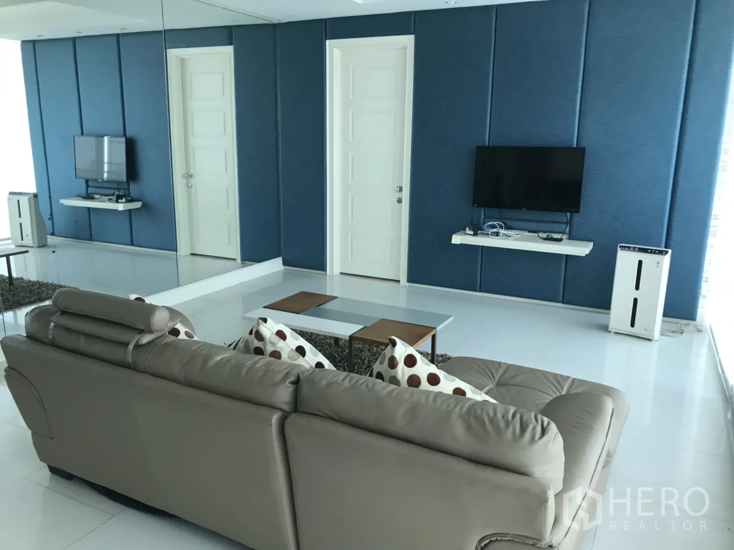 คอนโด ให้เช่าในWatthana, Bangkok - ผนังทีวีลายแผงสีฟ้า กระจกบานใหญ่ และโซฟาในห้องนั่งเล่นสว่างโปร่ง