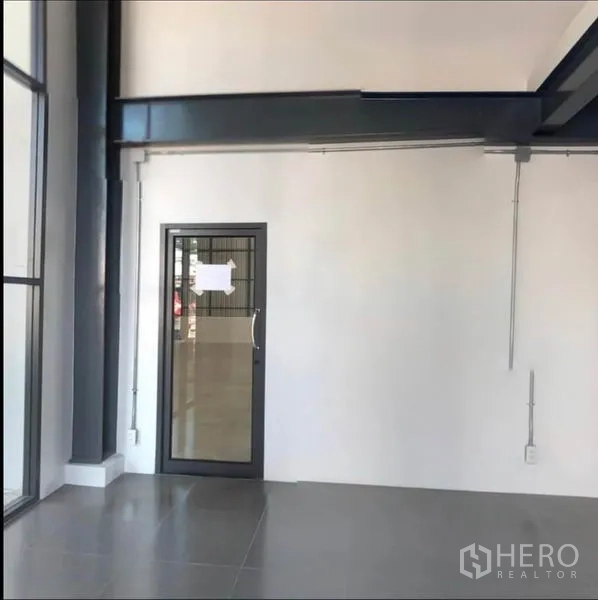 Office Space for rent in Wang Thonglang, Bangkok - High-ceiling entrance zone with glass door and steel beams in a contemporary workspace.