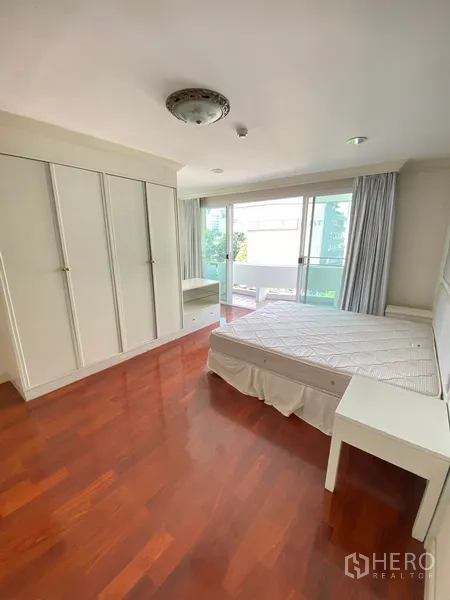 อพาร์ทเมนท์ ให้เช่าในWatthana, Bangkok - ห้องนอนหลักพื้นไม้ ตู้เสื้อผ้าบิลท์อินสีขาว และทางออกสู่ระเบียง