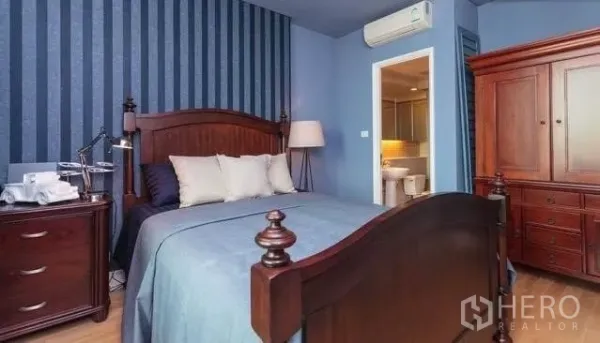 Condominium for rent or sale in Khlong Toei, Bangkok - Third bedroom in blue tones with wooden bed, wardrobe, and ensuite entrance.